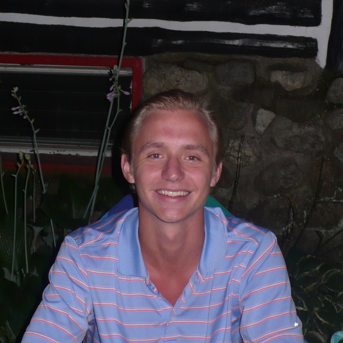 A picture of me smiling and sitting down at a cabin.